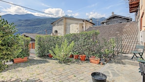 Une cour intérieure agrémentée de plantes en pot, dotée d’un sol en pierre et offrant une vue sur les montagnes.