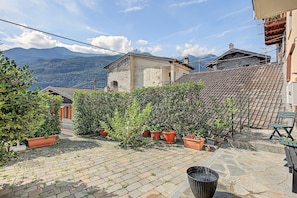A courtyard with potted plants, a stone floor, and a view of mountains.
