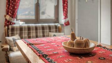 Een kamer met een houten tafel, een tapijt met rood patroon en een raam met gordijnen.