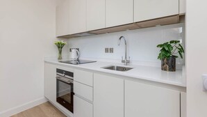 Een moderne keuken met witte kasten, een roestvrijstalen spoelbak en een inbouwoven.