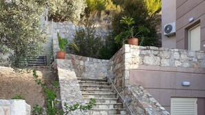 Eine Steintreppe führt zu einem Gebäude, am Fuß befinden sich Kübelpflanzen.