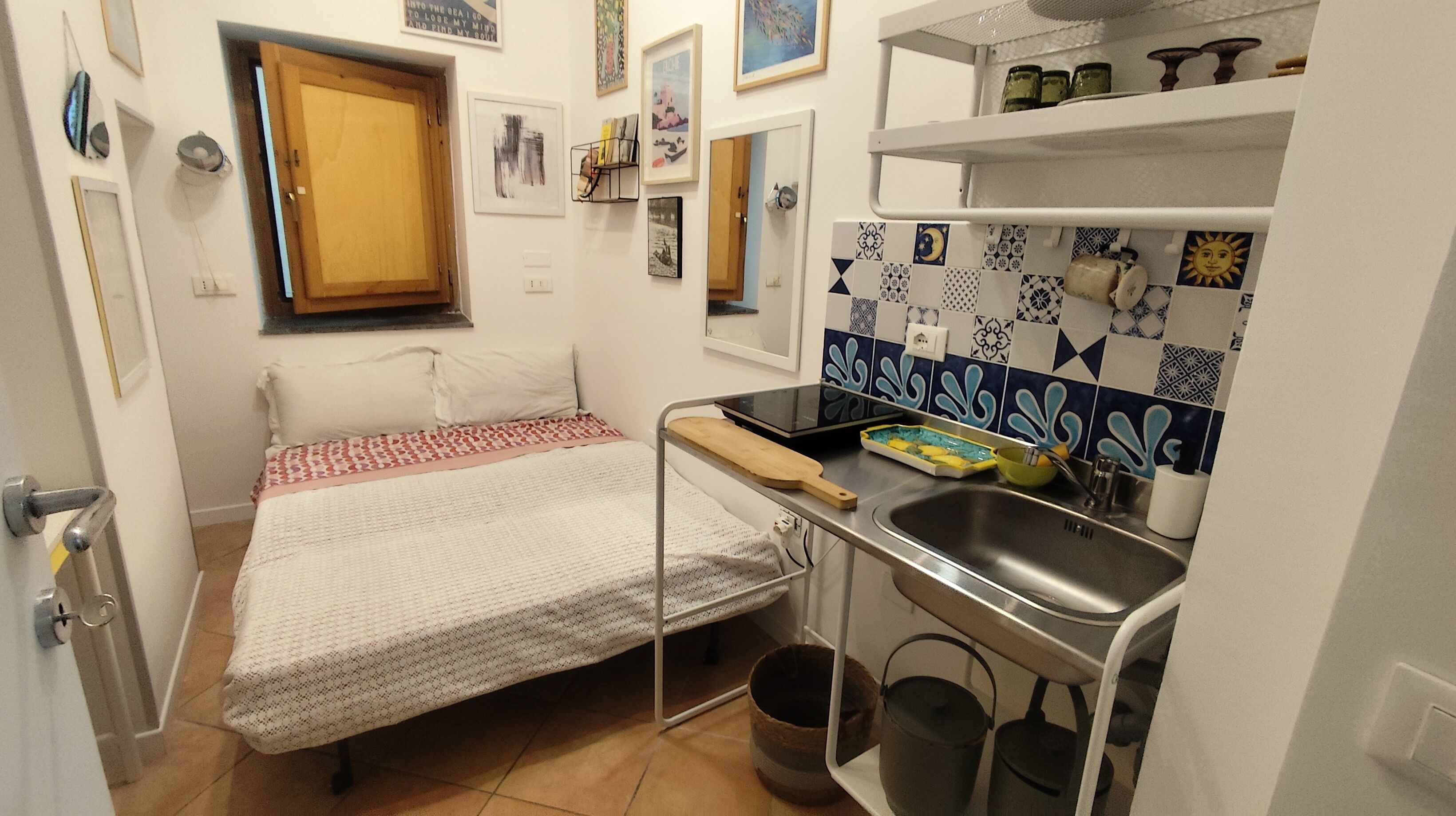 Una habitación funcional con cama, kitchenette pequeña y baño.