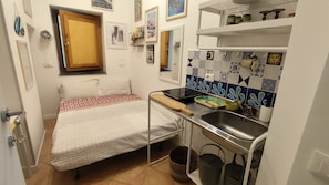 A compact room with a bed, a small kitchenette, and a bathroom. - Terrazza Malù - A charming little house in Salerno on the Amalfi Coast (Salerno)