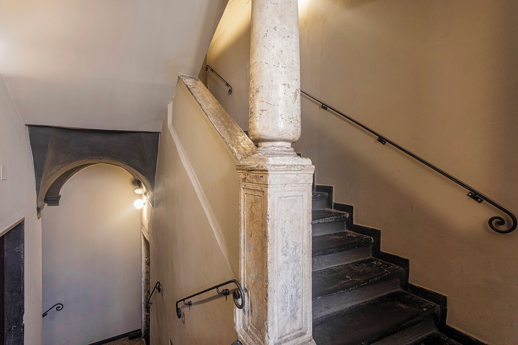 Una scala con corrimano, balaustra e un lampadario in cima.