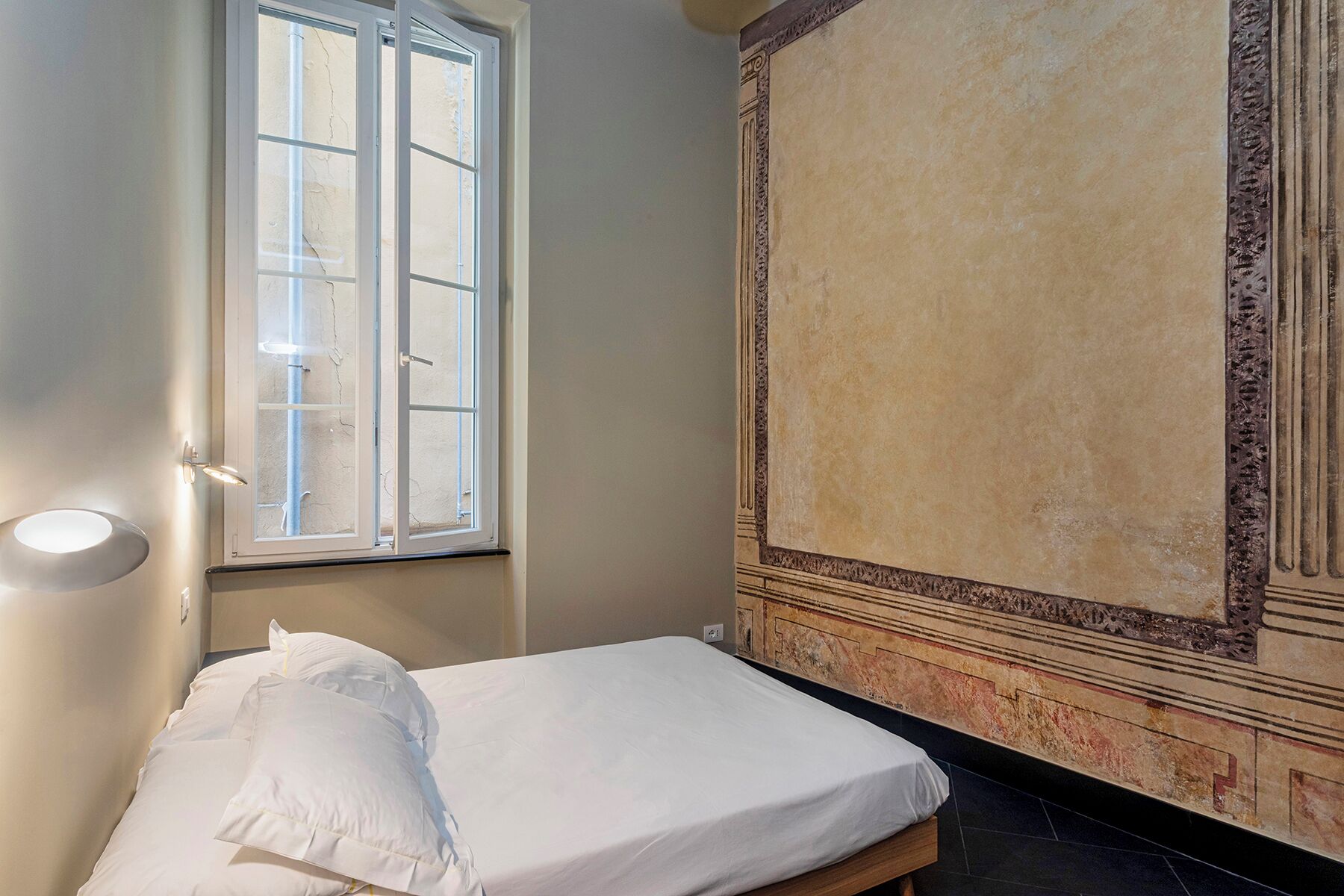Een kamer met een bed, een raam en decoratieve wand.
