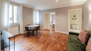 Una habitación con una mesa de comedor, un sofá verde y un radiador.