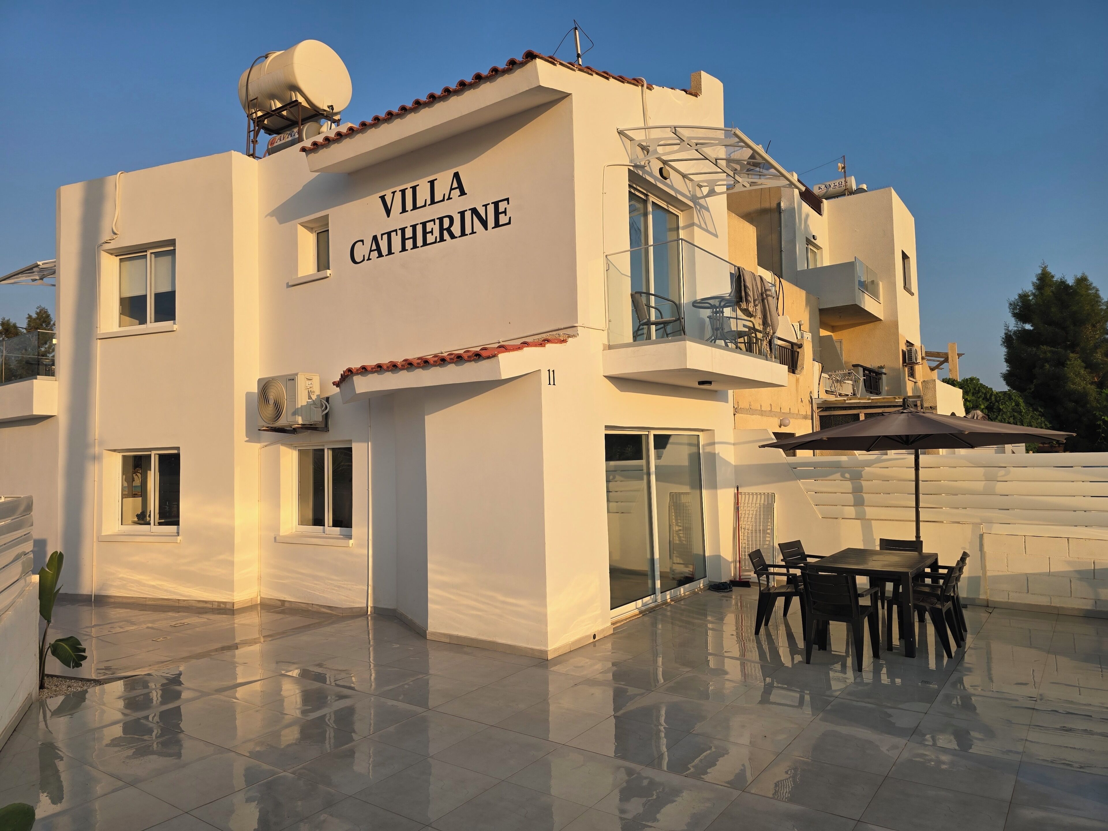 Una villa moderna llamada 'Villa Catherine', con balcón, mobiliario exterior y antena parabólica.
