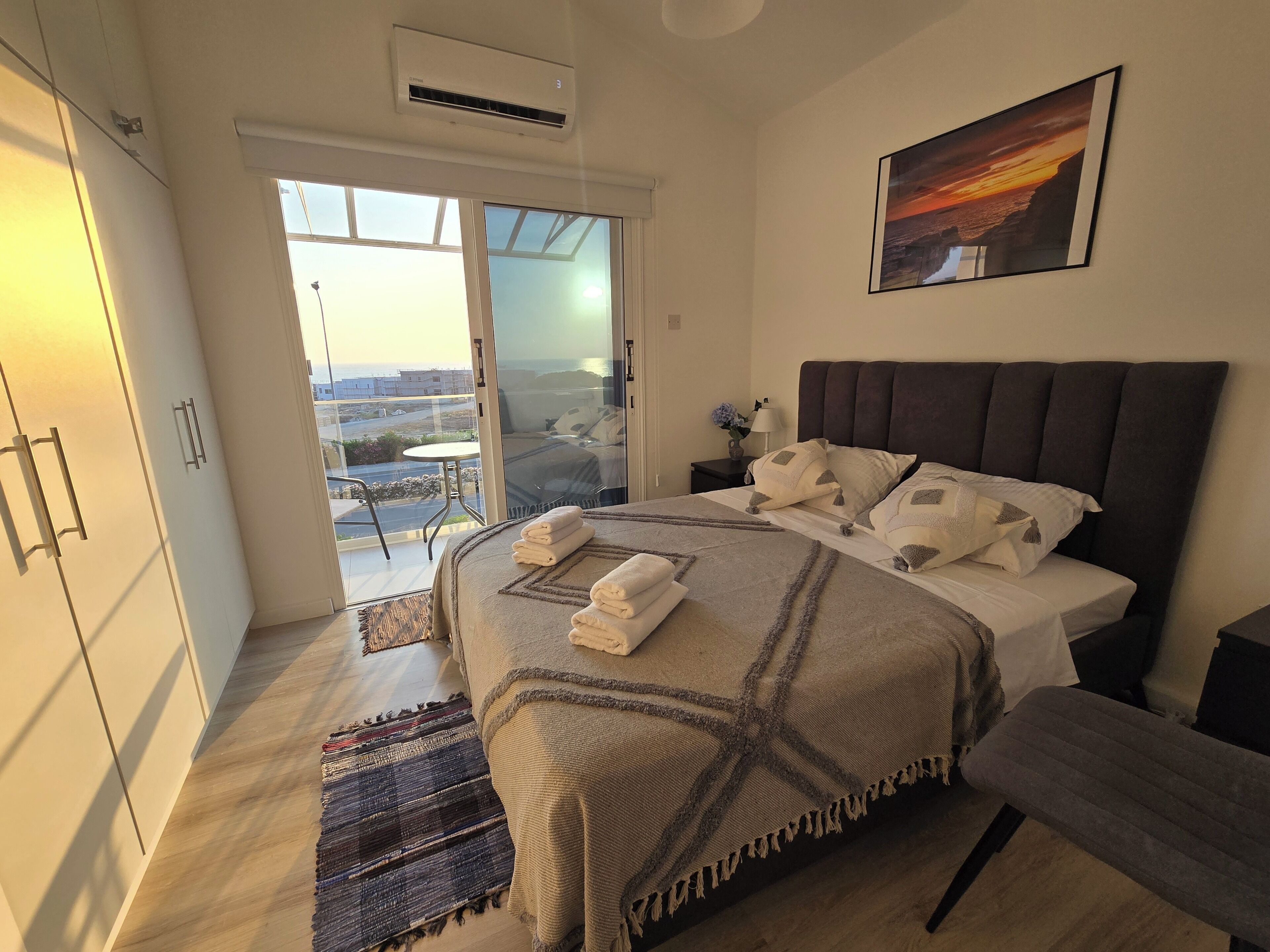 Une chambre à coucher avec un lit, une table de chevet, une commode, une fenêtre et une vue sur l’extérieur.