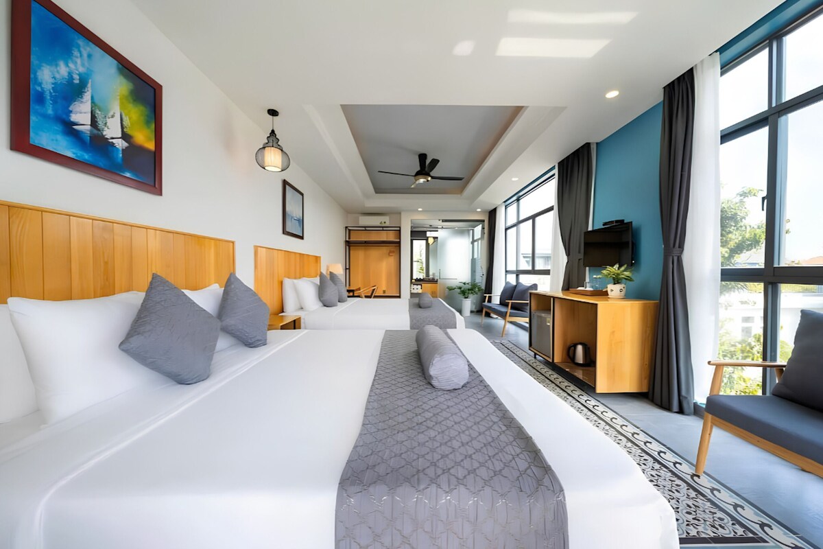 A modern hotel room with a large bed, a desk, a chair, and a view of the city.