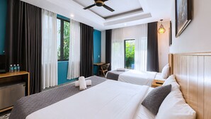 A hotel room with two beds, a ceiling fan, a desk with a chair, and a view of greenery outside. - Summer Beach Villa An Bang (Da Nang)