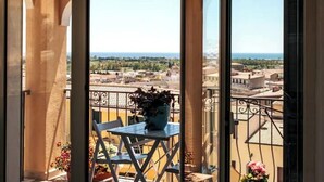 A balcony with a view of a cityscape, a table with a potted plant, and a chair. - A rare find in the historic center: ocean view, private parking, and 3 terraces (Orosei)