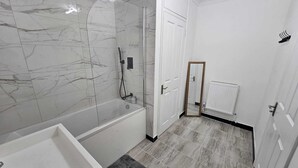 Un bany modern amb banyera, dutxa i vàter.