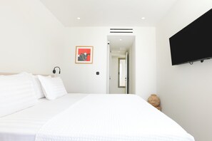 A modern hotel room with a large bed, a flat-screen TV mounted on the wall, and a framed picture on the wall. - Villa Noema, Luxury Villa (Corfu)
