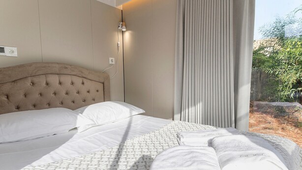 A bed with a tufted headboard, white linens, and a patterned bedspread.
