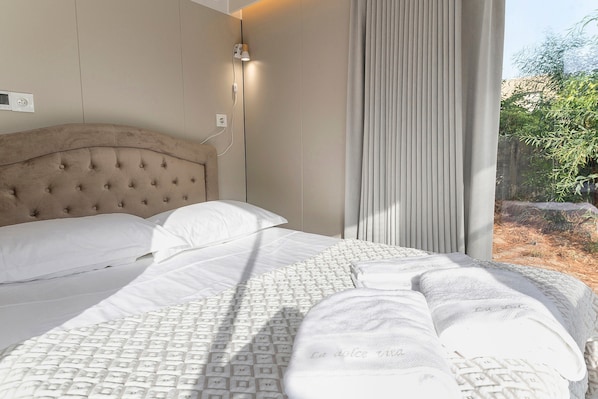 A bed with a tufted headboard, white linens, and a patterned bedspread.