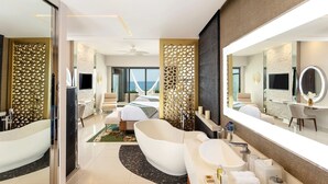 Ein modernes Hotelzimmer mit einer großen Badewanne, einer separaten Duschkabine, einem großen Spiegel und Meerblick.