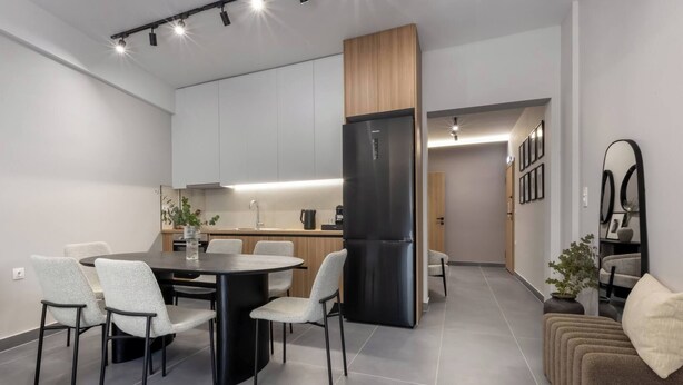 Eine moderne Küche mit Kochinsel, eingebauten Schränken und einem schwarzen Kühlschrank.