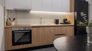 Eine moderne Küche mit Holzschränken, einem schwarzen Backofen, einer Spüle und einem Kühlschrank.