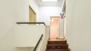 A staircase with wooden steps and a metal handrail, leading to a room with a pink wall and a door. - My Garden House USJ by Airhost (Subang Jaya)