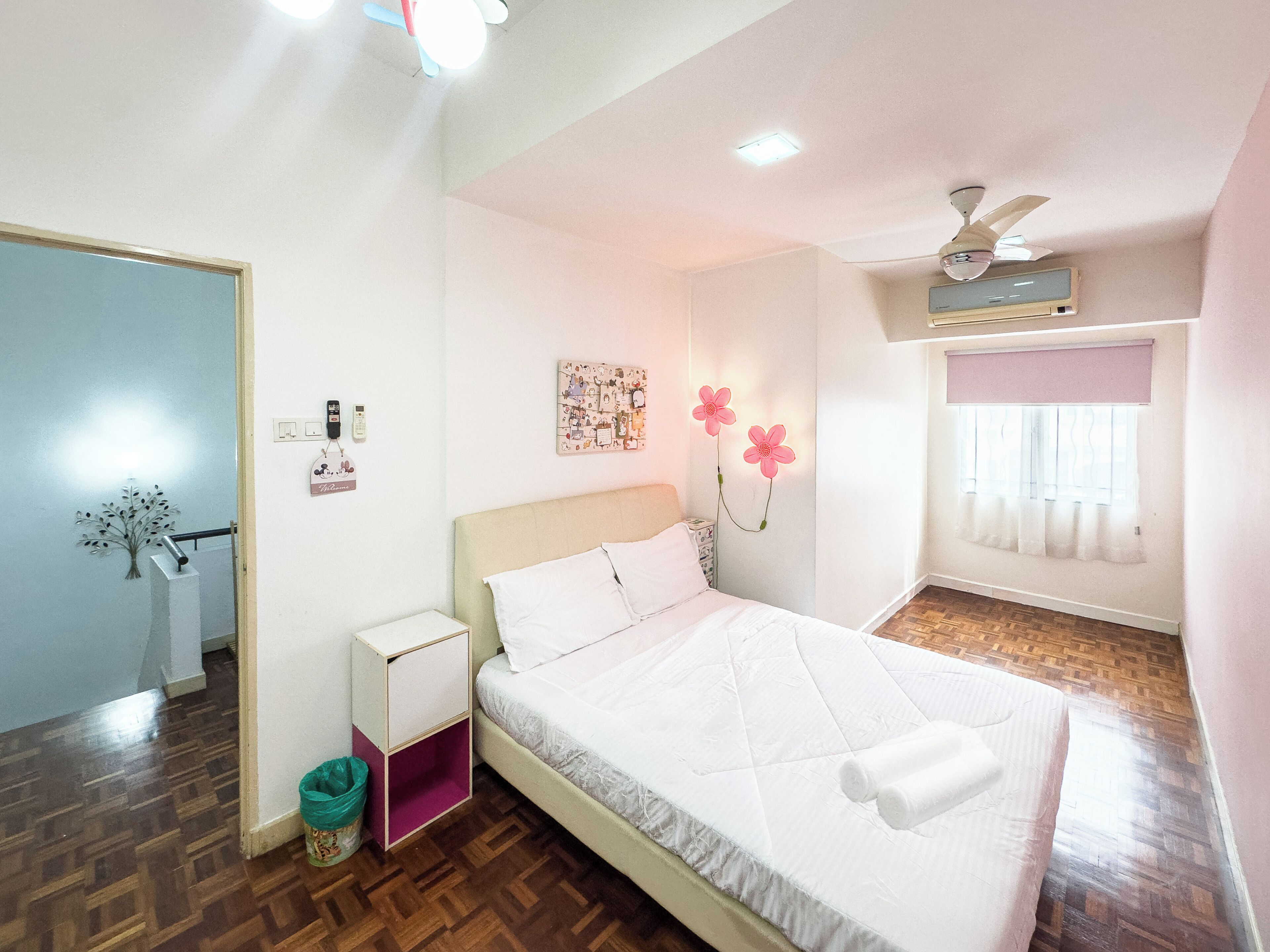 A bedroom with a bed, bedside table, wall-mounted phone, and a ceiling fan.