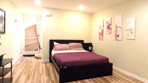 Un dormitorio con cama, una escalera y una puerta que da a otra habitación.
