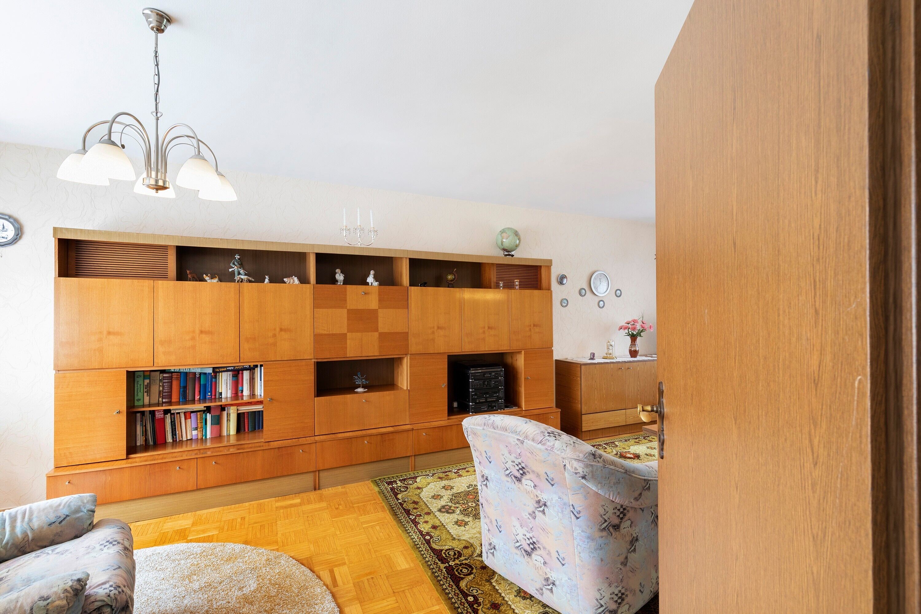 Una sala de estar con un aparador de madera, un sofá estampado, una mesa de centro de madera y una araña.