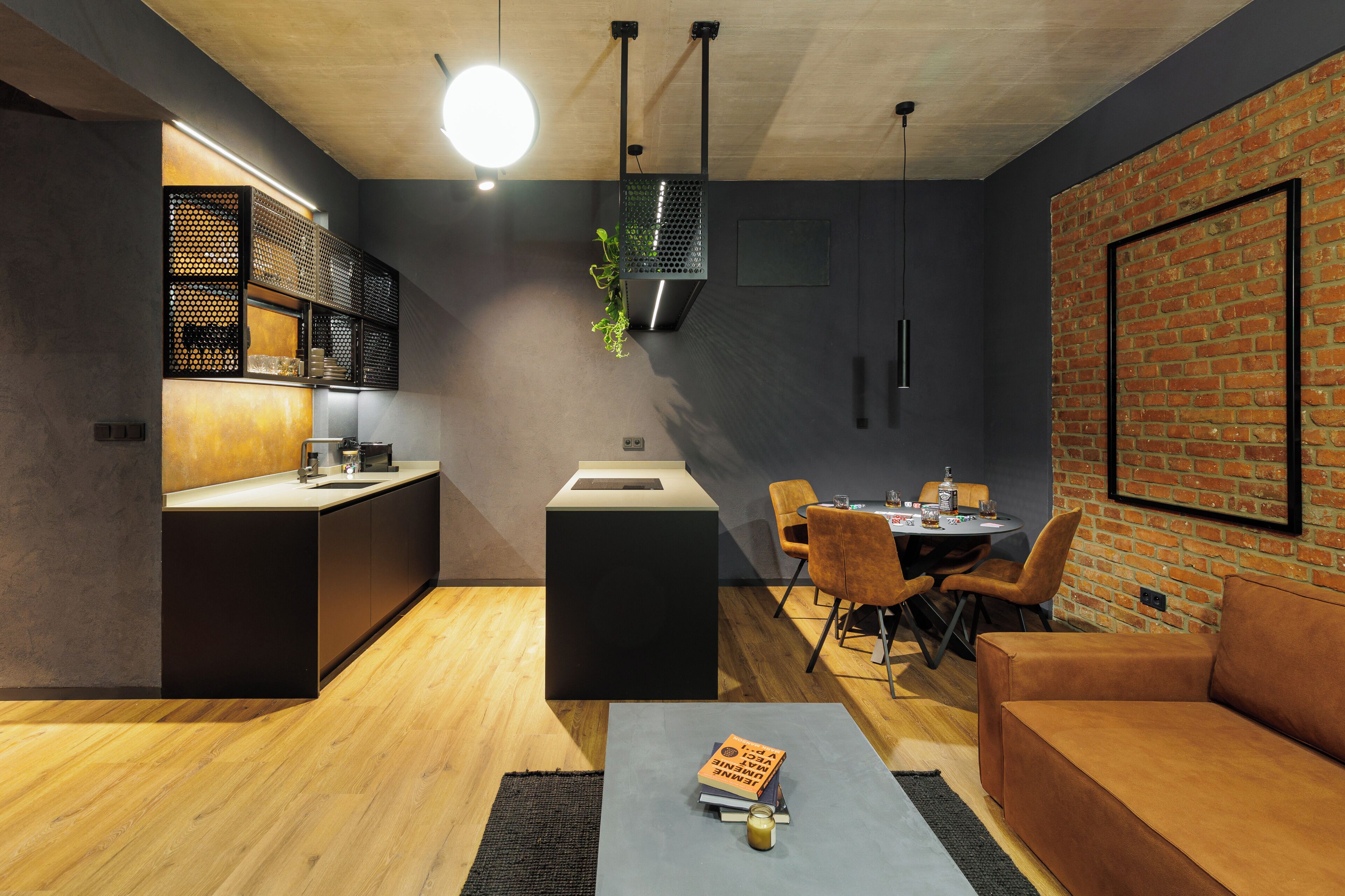 Una cocina moderna con una isla central, un comedor con pared de ladrillo y una zona de estar acogedora con sofá.