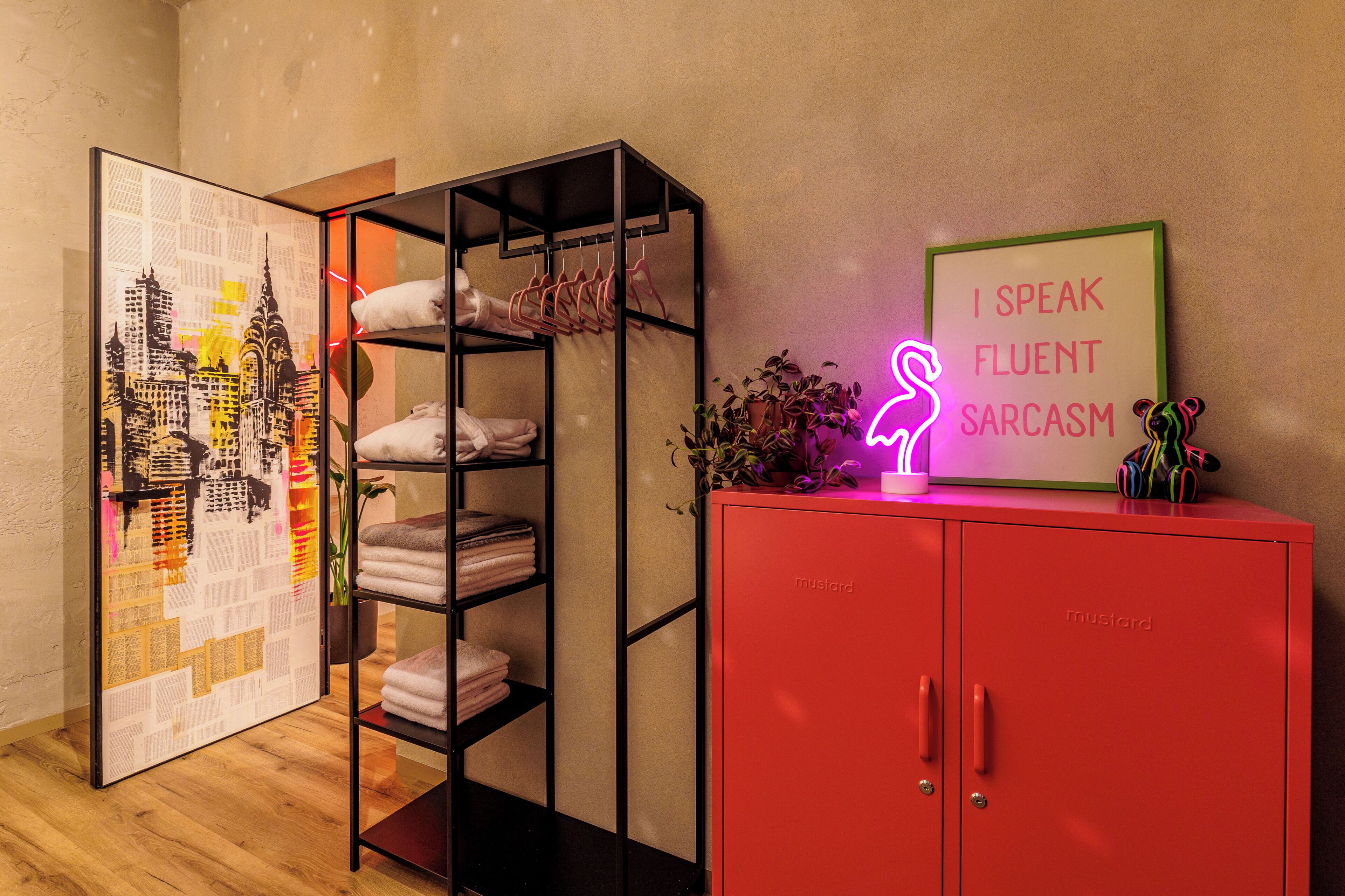 A room with a red cabinet, a neon sign, and a framed picture.