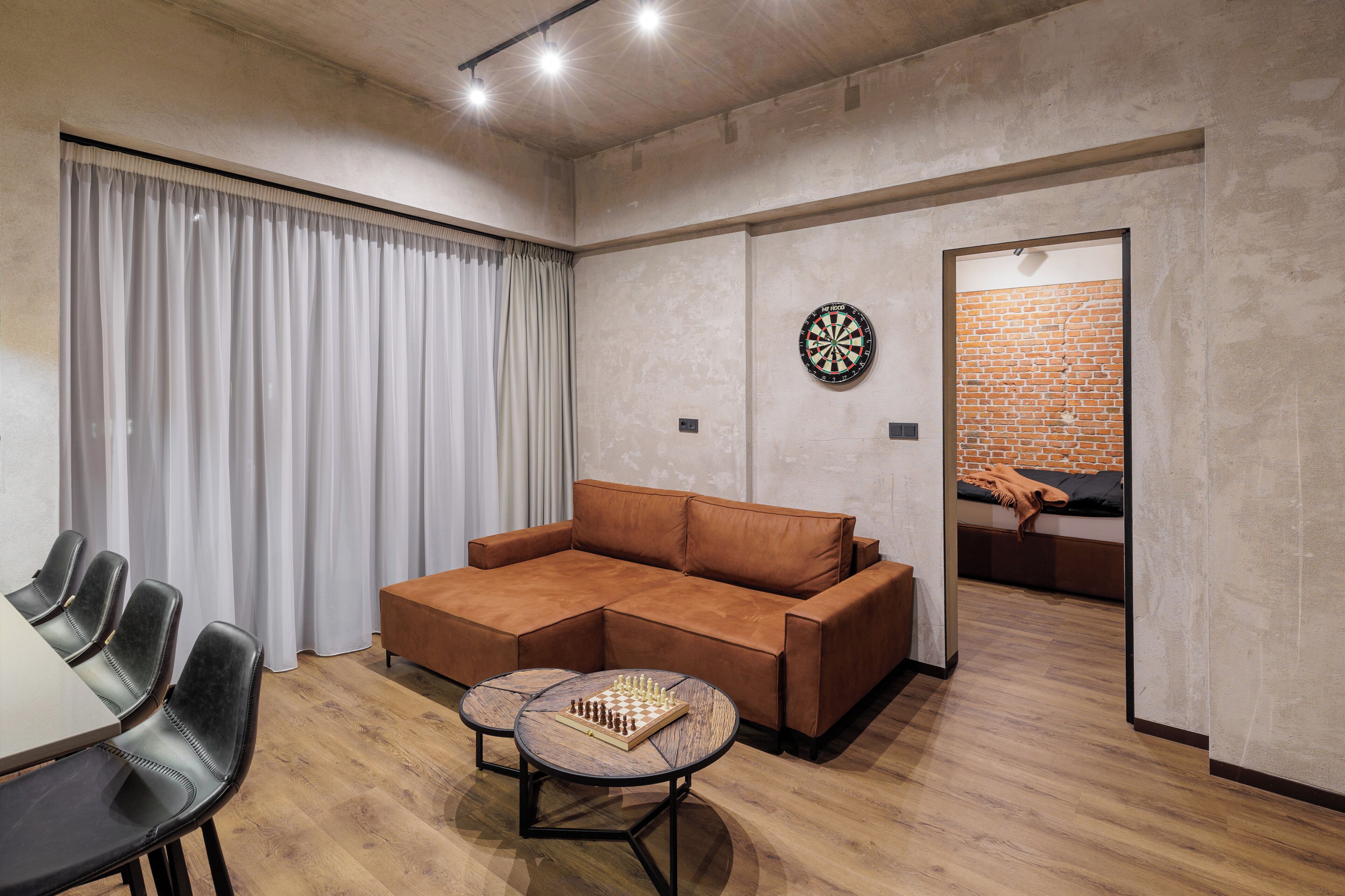 A modern living room with a sectional sofa, a round coffee table, and a dartboard.
