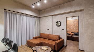 A modern living room with a sectional sofa, a round coffee table, and a dartboard.