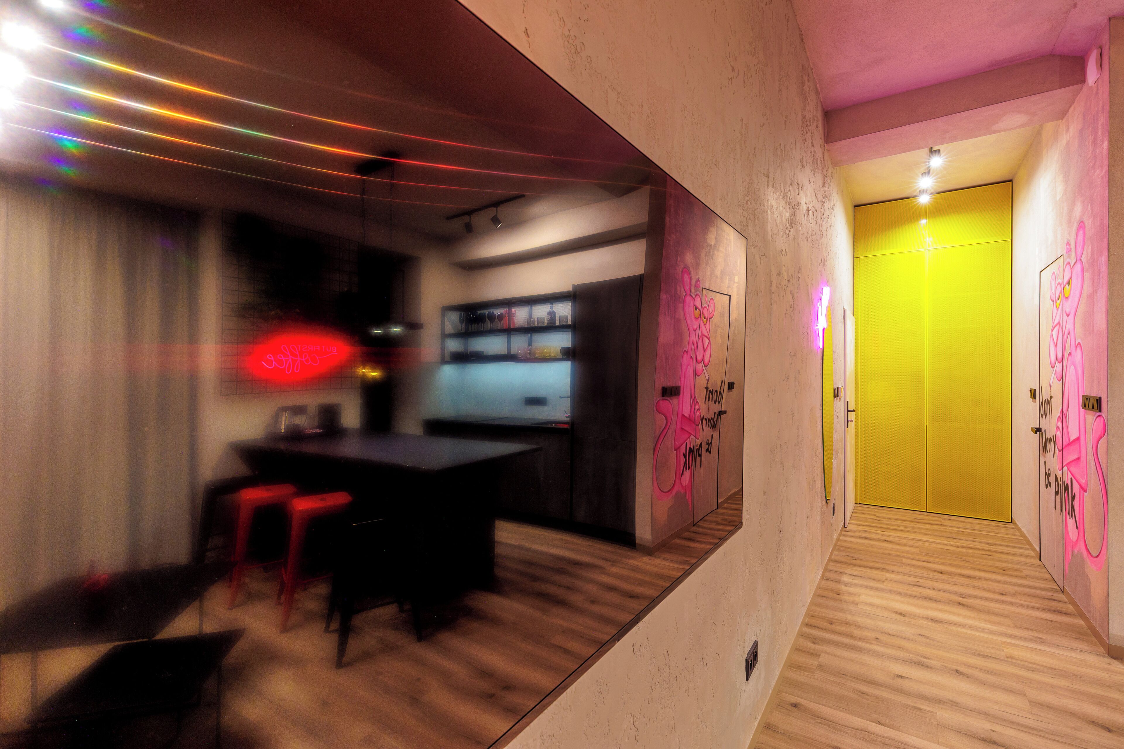 A modern interior with a bar area, wooden flooring, and a yellow door.