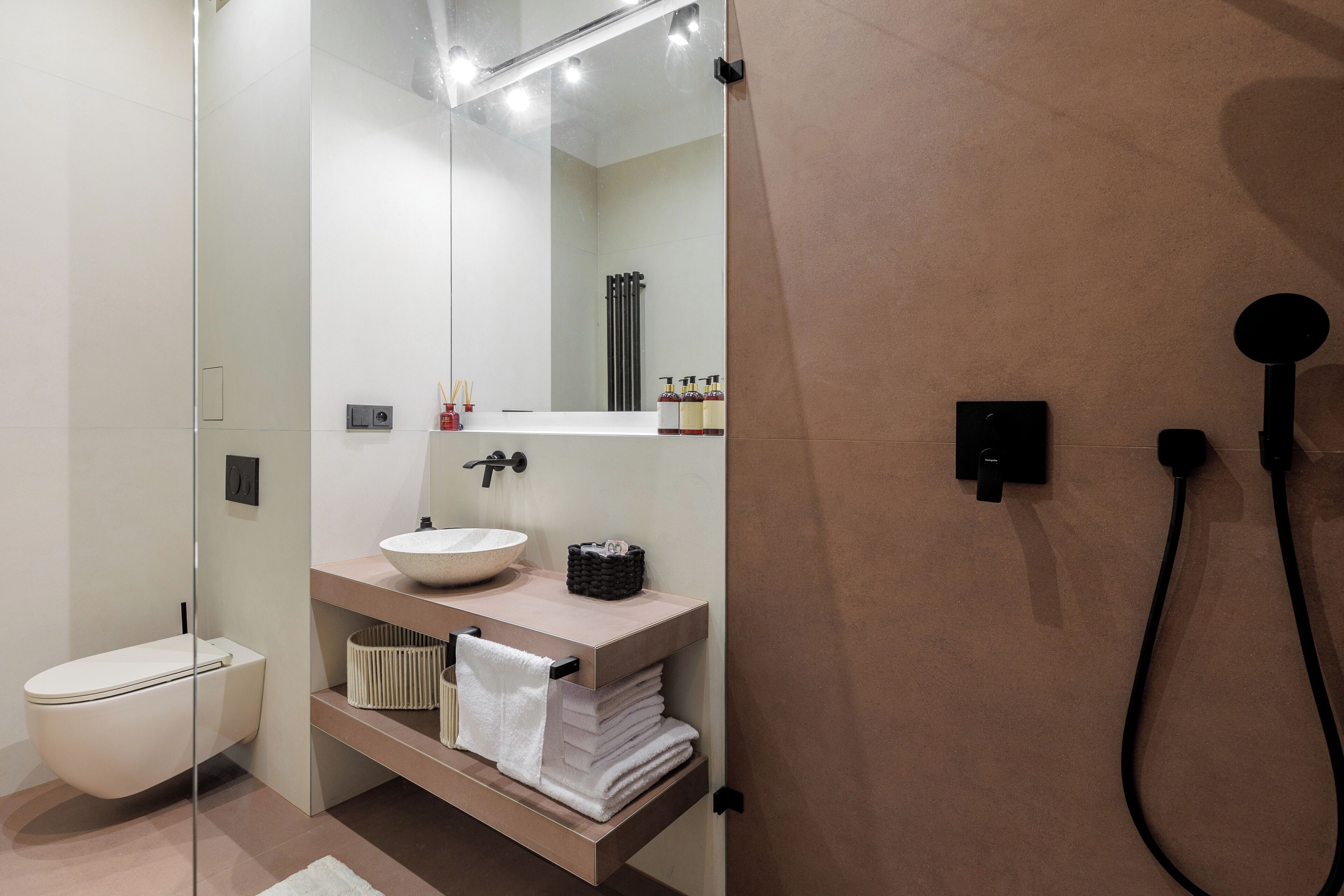 Un baño moderno con cabina de ducha de vidrio, inodoro blanco, lavabo con lavabo sobre encimera y toallero.