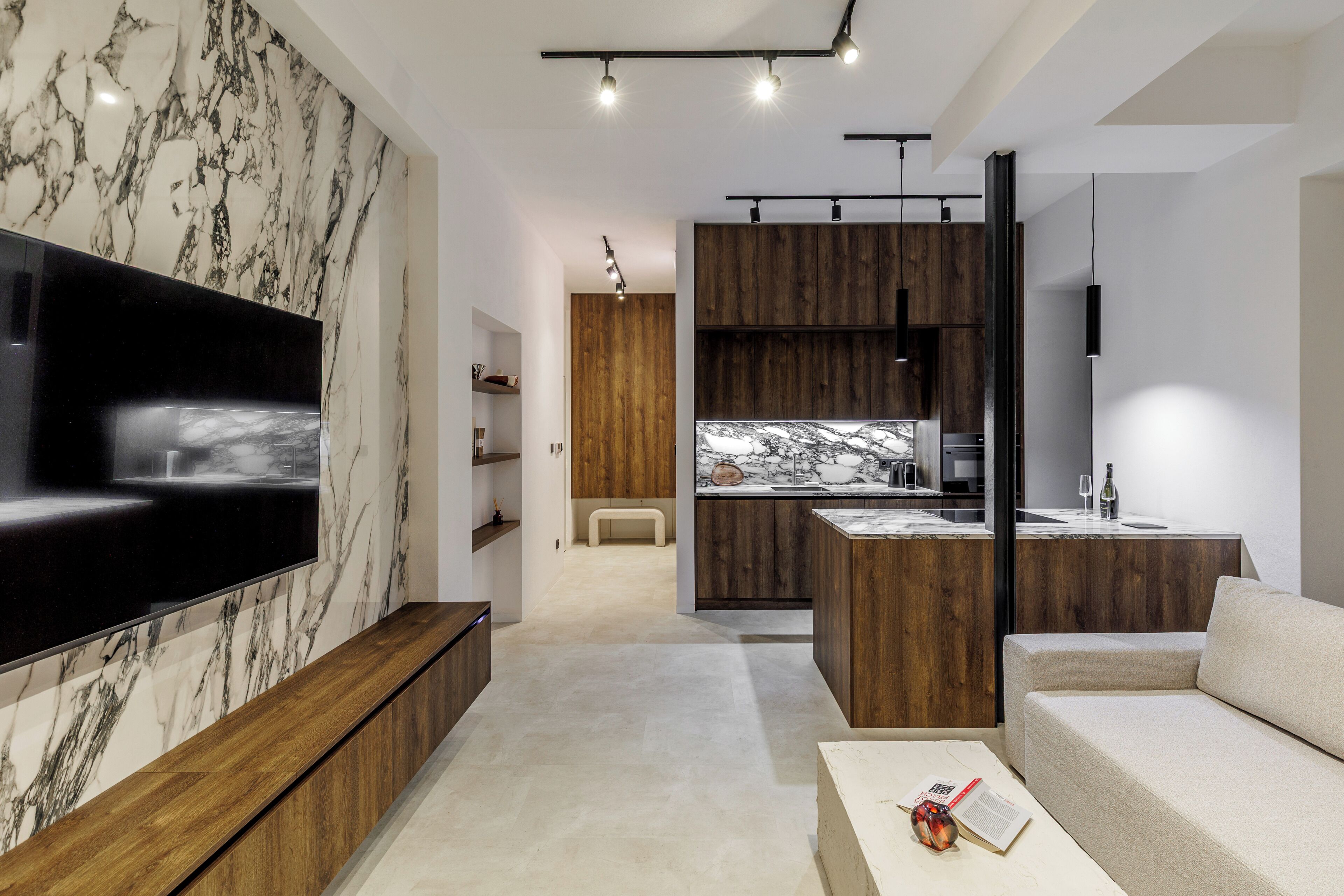 Uma sala de estar moderna com uma televisão de tela plana grande, armários de madeira, uma bancada de mármore e um sofá minimalista.