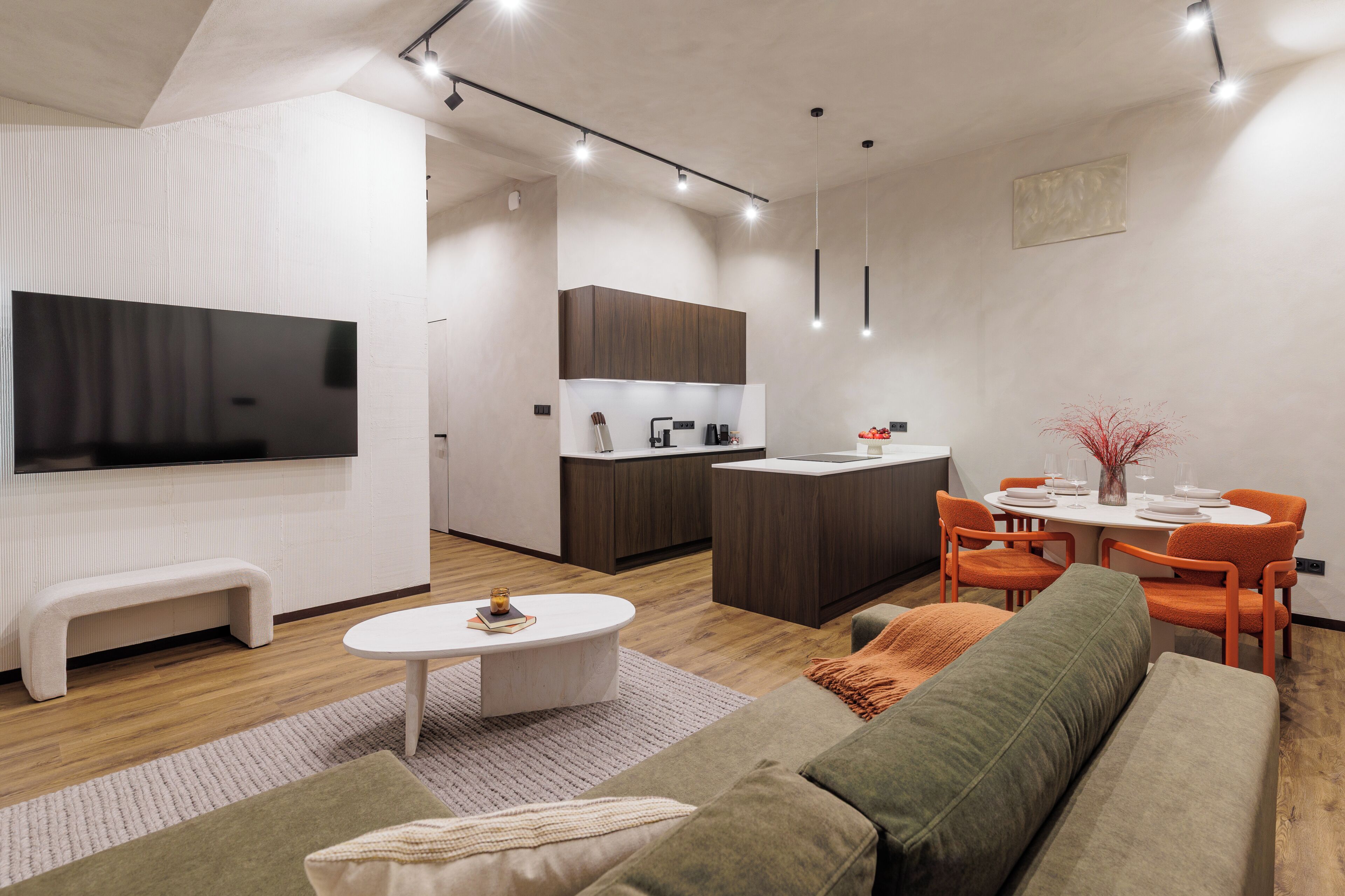 Ein modernes Wohnzimmer mit Flachbildfernseher, einer Couch, einem Couchtisch und einem Essbereich mit Tisch und Stühlen.