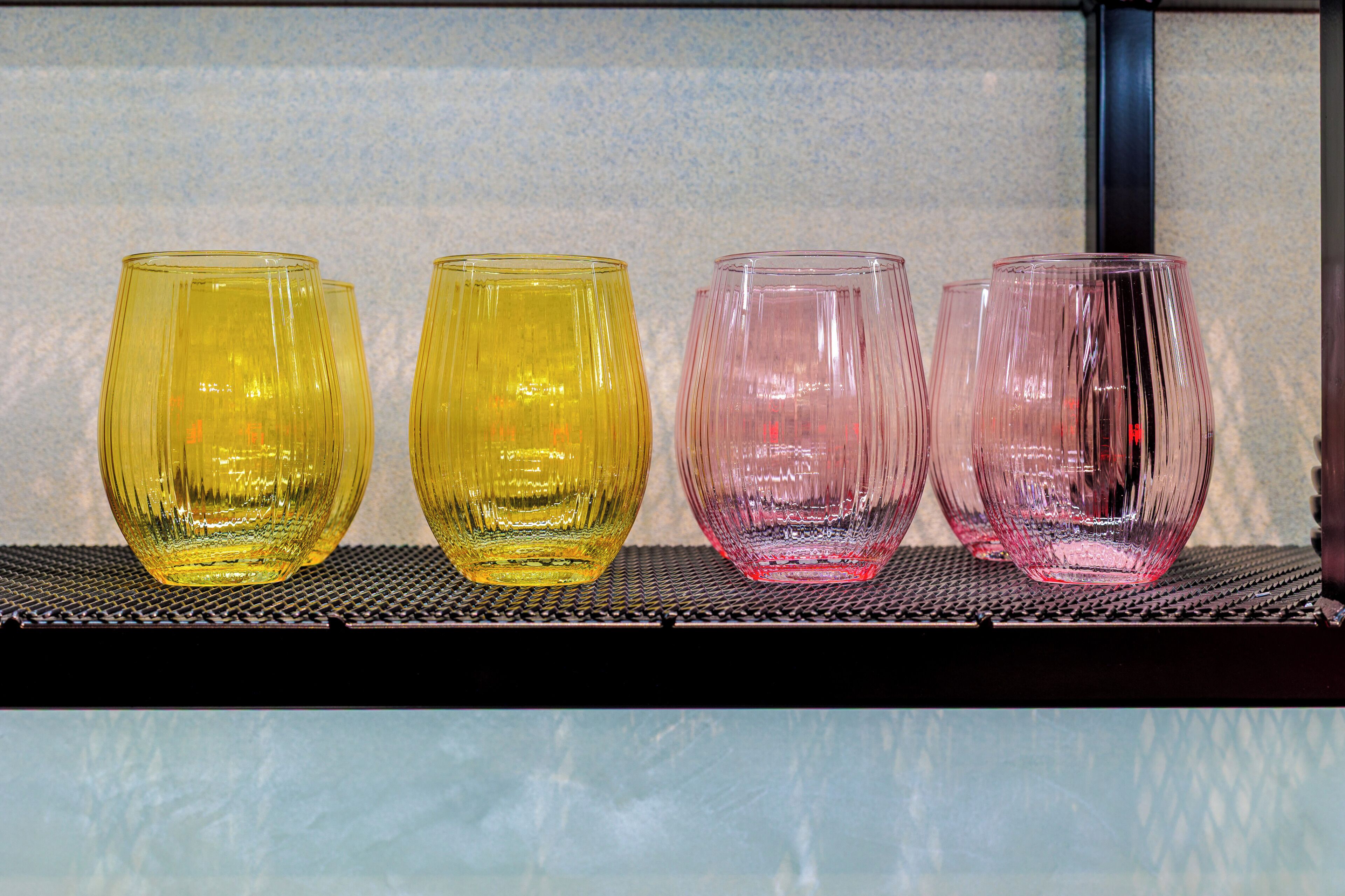Four glass tumblers on a shelf.
