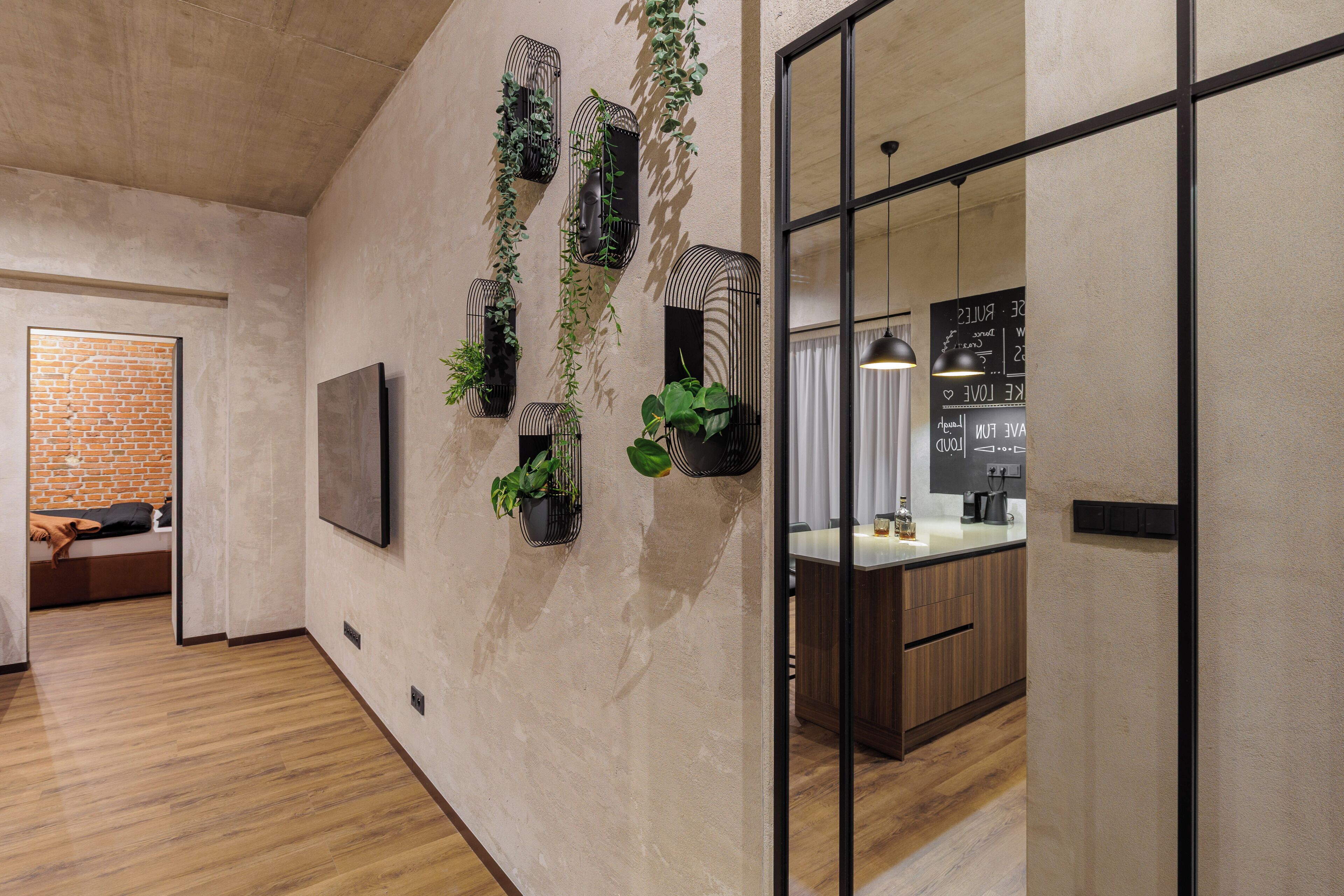 A modern interior with a kitchen, a dining area, and a living space with a brick wall and wooden flooring.