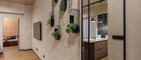 A modern interior with a kitchen, a dining area, and a living space with a brick wall and wooden flooring.