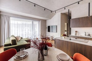 Uma sala de estar moderna com sofá, mesa de jantar e área de cozinha.