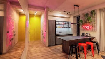 Cozinha moderna com ilha central, banquetas e um letreiro de neon.