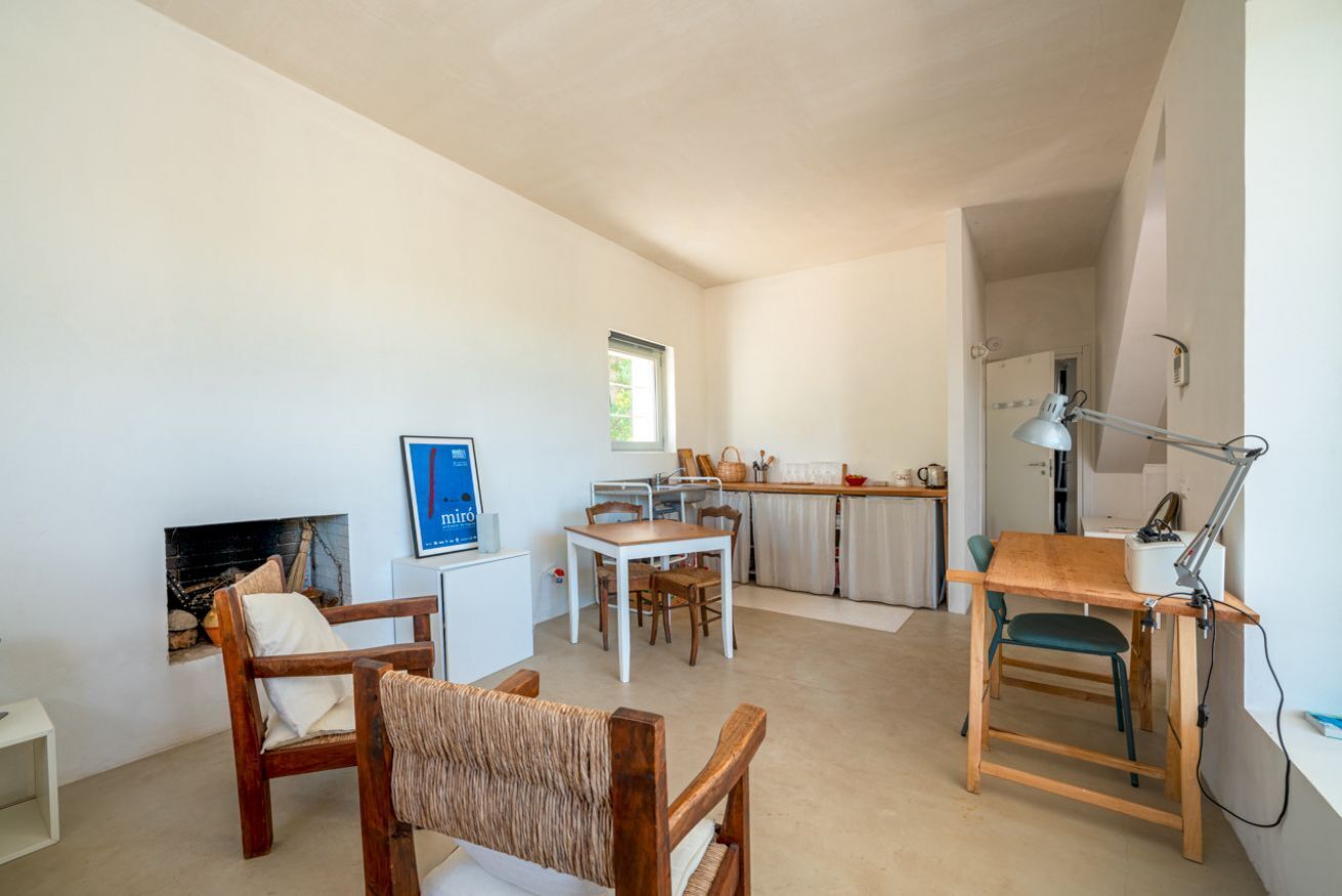Een knus woongedeelte met een open haard, een eethoek, een keuken en een werkplek met bureau en stoel.