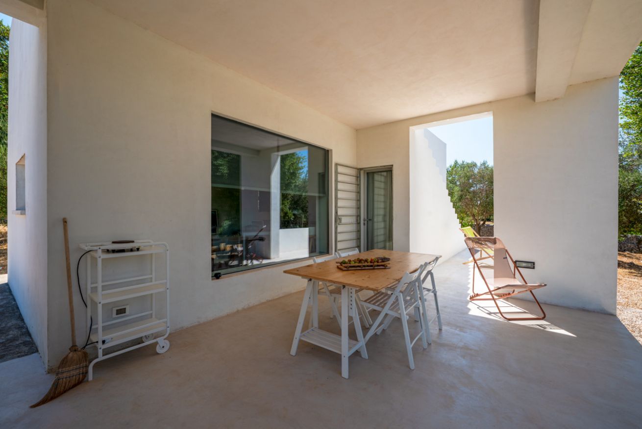 A modern outdoor dining area with a table and chairs, a broom, and a cart.