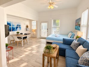 A modern, well-lit room with a dining area, a bed, and a blue sofa. - Stylish Studio w Patio Walk Downtown & Balboa Park (San Diego)