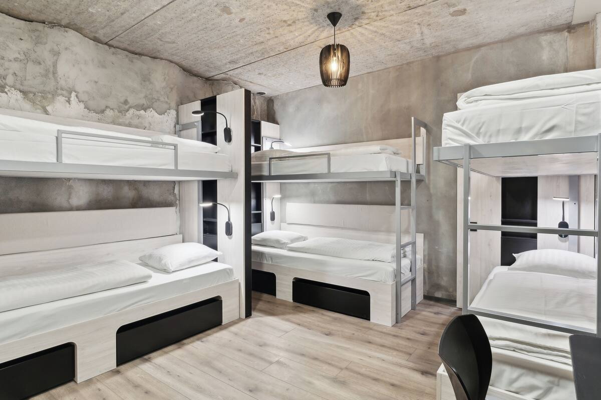 A bunk bed room with a concrete ceiling, a hanging light fixture, and a wooden floor.