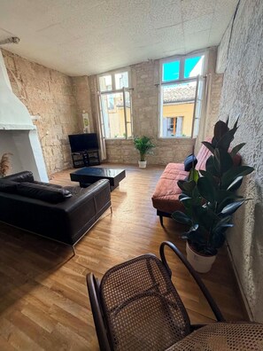 Ein Wohnzimmer mit einer Couch, einem Sessel, einem Fernseher und einer Topfpflanze.