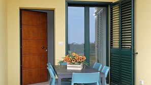 Une pièce avec une porte en bois, une porte-fenêtre coulissante, une table avec des chaises et un arrangement floral.