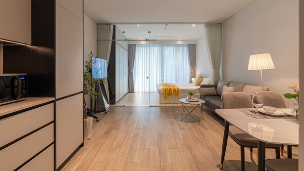 Una sala de estar moderna con sofá, mesa de comedor y zona de cocina.