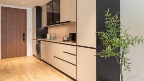 Una cocina moderna con horno integrado, lavadora y una planta.