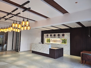 A hotel reception area with a modern design, featuring a marble reception desk, a wall with clocks showing different cities, and a ceiling with exposed beams and hanging light fixtures. - Hotel Tulip Hyderabad Airport Zone (Hyderabad)