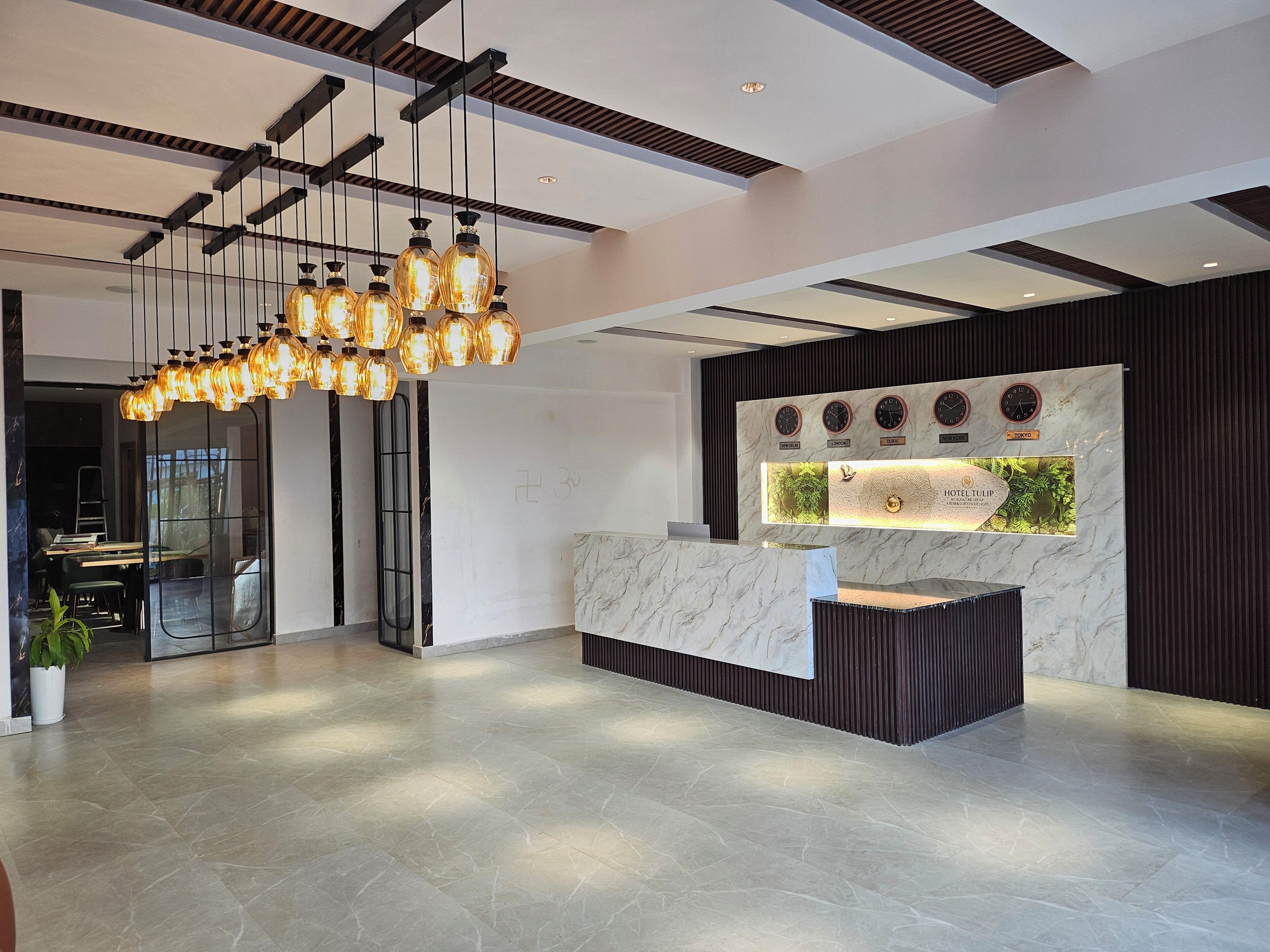 A modern hotel reception area with a marble counter, a wall clock, and a unique light fixture.