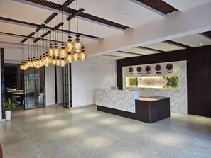 A modern hotel reception area with a marble counter, a wall clock, and a unique light fixture. - Hotel Tulip Hyderabad Airport Zone (Hyderabad)